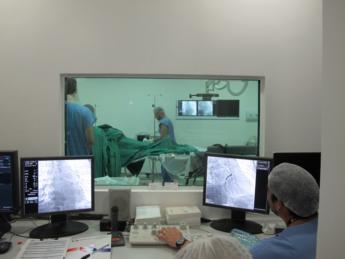 Realização de um exame de cateterismo, visto da sala de operações do maquinário.